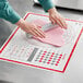 A person using an OXO Good Grips silicone pastry mat to roll out pink dough.