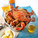 A bushel of Chesapeake blue crabs and corn on a blue tablecloth.