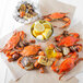 A group of large steamed Chesapeake blue crabs and corn on the cob on a table.