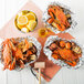 Three Chesapeake Crab Connection aluminum foil containers of extra seasoned steamed blue crab with lemons.