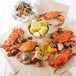 A table with a bushel of large and extra large seasoned steamed blue crabs, corn on the cob, and lemons.