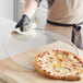 A person holding a pizza on a Choice aluminum pizza screen.