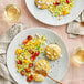 Two plates of Chesapeake Crab Connection blue crab cakes with corn and tomatoes on the table.