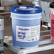 A blue bucket of Advantage Chemicals low temperature concentrated dish washing machine rinse aid with a white label.