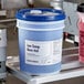 A blue and white bucket of Advantage Chemicals Low Temperature Rinse Aid.