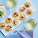 A plate with mini crab cakes and lump crab meat with purple garnish on a blue table.