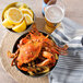 A bowl of seasoned steamed blue crab and lemons on a table.