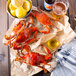Steamed Chesapeake blue crabs on paper next to a bowl of lemons and a bucket of beer.