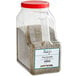 A large plastic container of Regal Pizza Seasoning with a red lid containing green and brown spices.