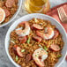 A plate of rice with shrimp and sausage next to a glass of wine.