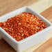 A white square bowl of orange and white powder with orange and white flakes.