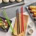 A table set with Emperor's Select red melamine chopsticks, plates, and bowls of food.