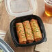 A Choice plastic container with fried food and a drink with a straw on a table.