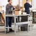 A man in a black shirt opening a box to install a Lavex steel workbench top.