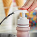 A hand using a LorAnn white dispenser pump to pour liquid onto ice cream.