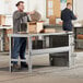 A man opening a brown box on a table.