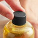 A hand holding a bottle of liquid with a black plastic 24/410 continuous thread lid.