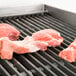 Raw meat on an APW Wyott Charbroiler grill over lava rocks.