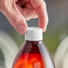 A person's hand holding a white plastic bottle with a white 28/410 continuous thread lid.