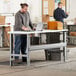 A person using a laptop at a white Lavex adjustable height workbench with black legs.