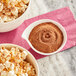 A bowl of popcorn and a bowl of brown Carnival King Chipotle Popcorn Seasoning powder.