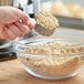 A person holding a measuring cup of brown powder over a bowl of dough.