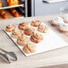 A table with a white Double-Wall Corrugated Half Sheet Cake Pad holding cinnamon rolls on a table in a bakery display.