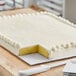 A white sheet cake with frosting on a white Double-Wall Corrugated Full Sheet Cake Board.