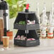 A black ServSense lazy susan countertop organizer with condiments in it.