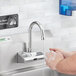 A person washing their hands under a Waterloo hands-free faucet.