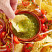 A hand dipping a chip into a bowl of tomatillo salsa.