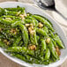 A bowl of sugar snap peas with sesame seeds on top.