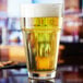 An Anchor Hocking stackable cooler glass filled with beer on a table.