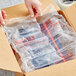 A hand opening a box of Pregis AirSpeed Mini Pak'r clear plastic cushion film rolls.