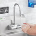 A person washing their hands under a Waterloo hands-free faucet.