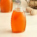 A Classic Queenline PET honey bottle on a table next to a jar of honey.