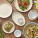 A table set with white Acopa stoneware plates, bowls, and utensils.