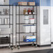 A black epoxy 5-shelf wire shelving unit with casters, used for storage in commercial settings.