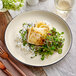 An Acopa Embers matte coupe stoneware plate with a plate of food and a fork on a table.