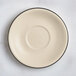 A cream white Acopa Embers stoneware saucer with black speckled edges.