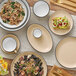 An Acopa Embers Harvest Tan Matte stoneware plate on a table with food.