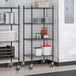 A black epoxy 4-shelf wire shelving unit with casters, used for storage in commercial settings.