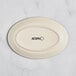 An Acopa cream white matte coupe stoneware platter with black text reading "Acopa" on the bottom.