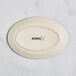 A white oval Acopa stoneware platter with black text on it.