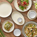 A table set with Acopa cream white stoneware platters, bowls, and plates with black rims.