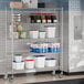 A Steelton wire shelving unit with casters in a school kitchen filled with containers.