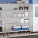 A chrome 5-shelf wire shelving unit with casters, used for storage in a commercial kitchen or similar setting.