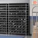 A Regency wire shelving unit with many black bins on it.