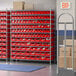 A Regency wire shelving unit with red bins on shelves in a warehouse.