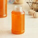 A jar of honey on a table next to a Skep PET sauce/honey bottle.